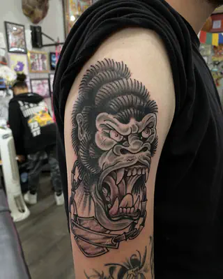 Black and grey traditional gorilla baring its teeth, on an upper arm