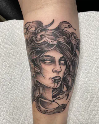 Black and grey tattoo of Medusa with a crown of snakes, on a forearm
