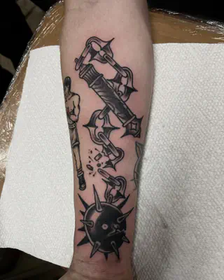 Blackwork tattoo of a medieval flail with a spiked ball on a chain, on a forearm