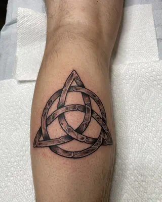 Celtic trinity knot tattoo in bold black line work, on a calf