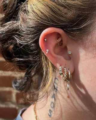 Ear with helix, conch, and stacked lobe piercings in silver