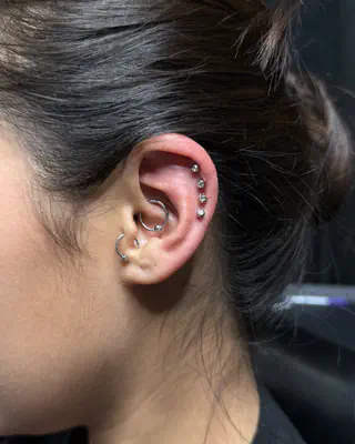 Ear with a row of helix studs, a conch hoop, and a tragus stud