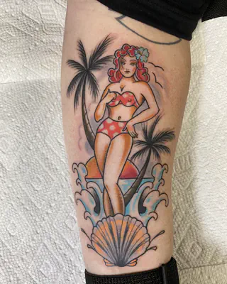 American traditional pin-up in a red polka dot bikini between palm trees, above a seashell, on a forearm