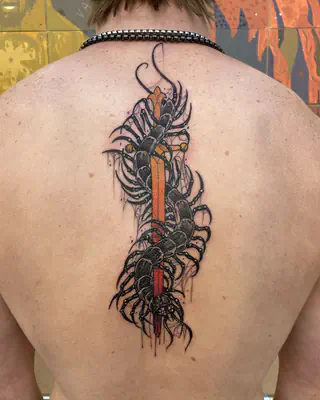 Tattoo down the spine of a black centipede coiled around a red dagger