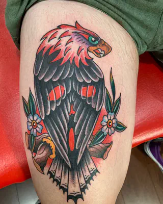 American traditional eagle in black and red with two blue flowers, on a thigh