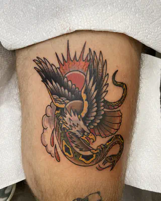 American traditional eagle fighting a snake in front of a rising sun, on a thigh