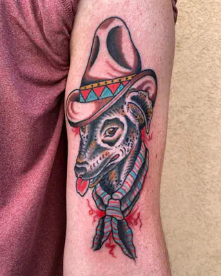 American traditional color tattoo of a goat in a pink cowboy hat and a patterned bandana, on an upper arm