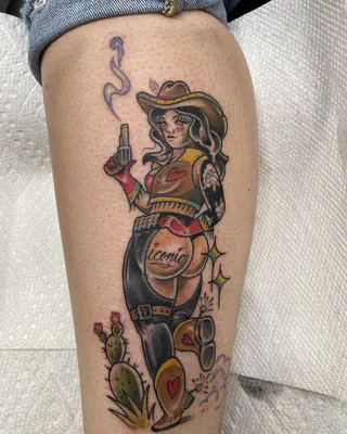 American traditional outlaw cowgirl holding a smoking pistol beside a cactus, on a calf