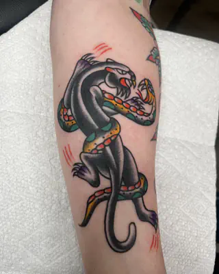 American traditional black panther wrestling a snake, on a forearm