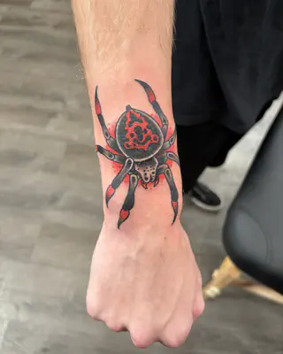 Traditional red and black spider on the back of a wrist