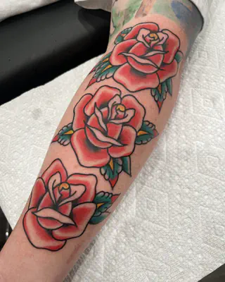 Three traditional red roses climbing a forearm