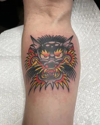 Traditional color tiger face in red, yellow, and black, on a forearm